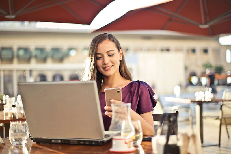 woman next to computer looking at phone